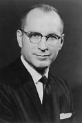 A person wearing glasses and a suit AI-generated content may be incorrect.